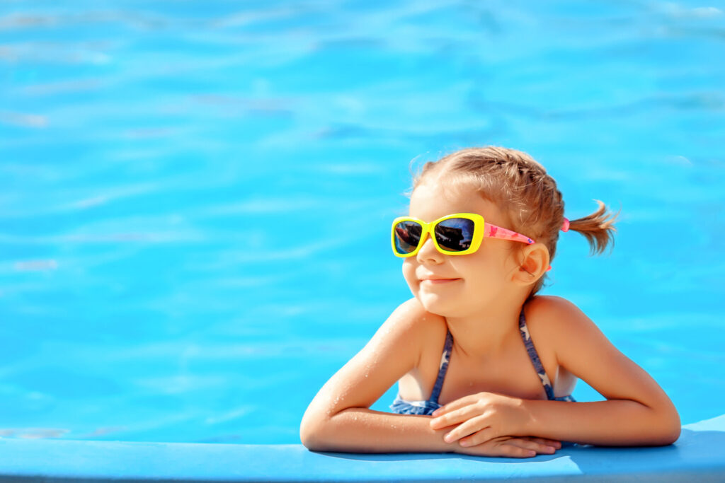 süßes kleines Mädchen mit Sonnenbrille im Pool