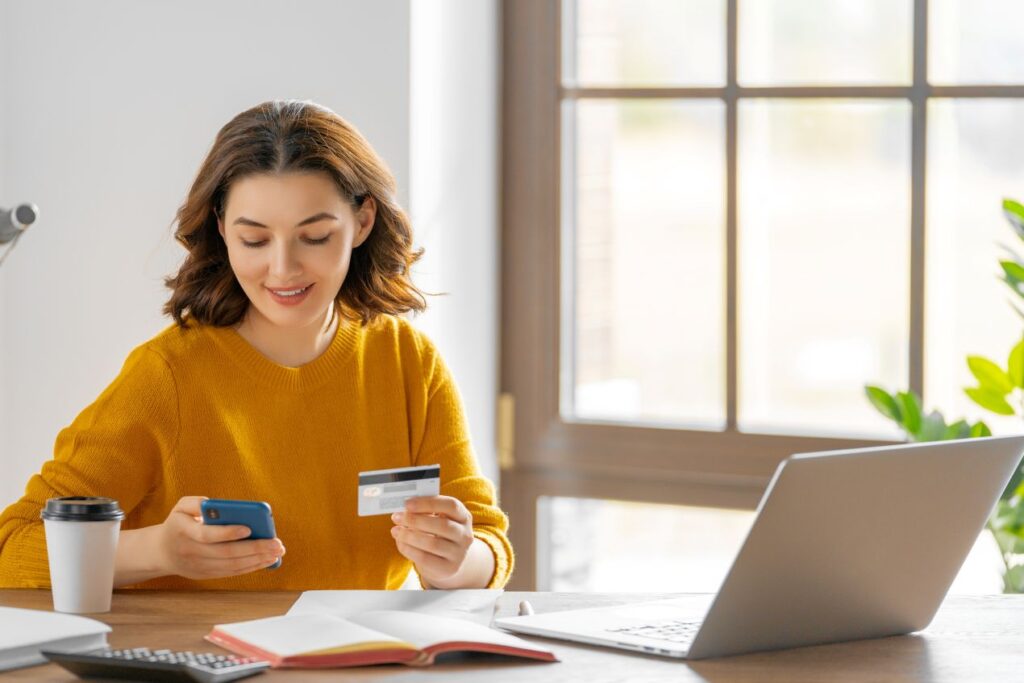 Frau bezahlt Elfbar Elfa online mit Kreditkarte und Smartphone – sicheres Bezahlen beim Internetshopping