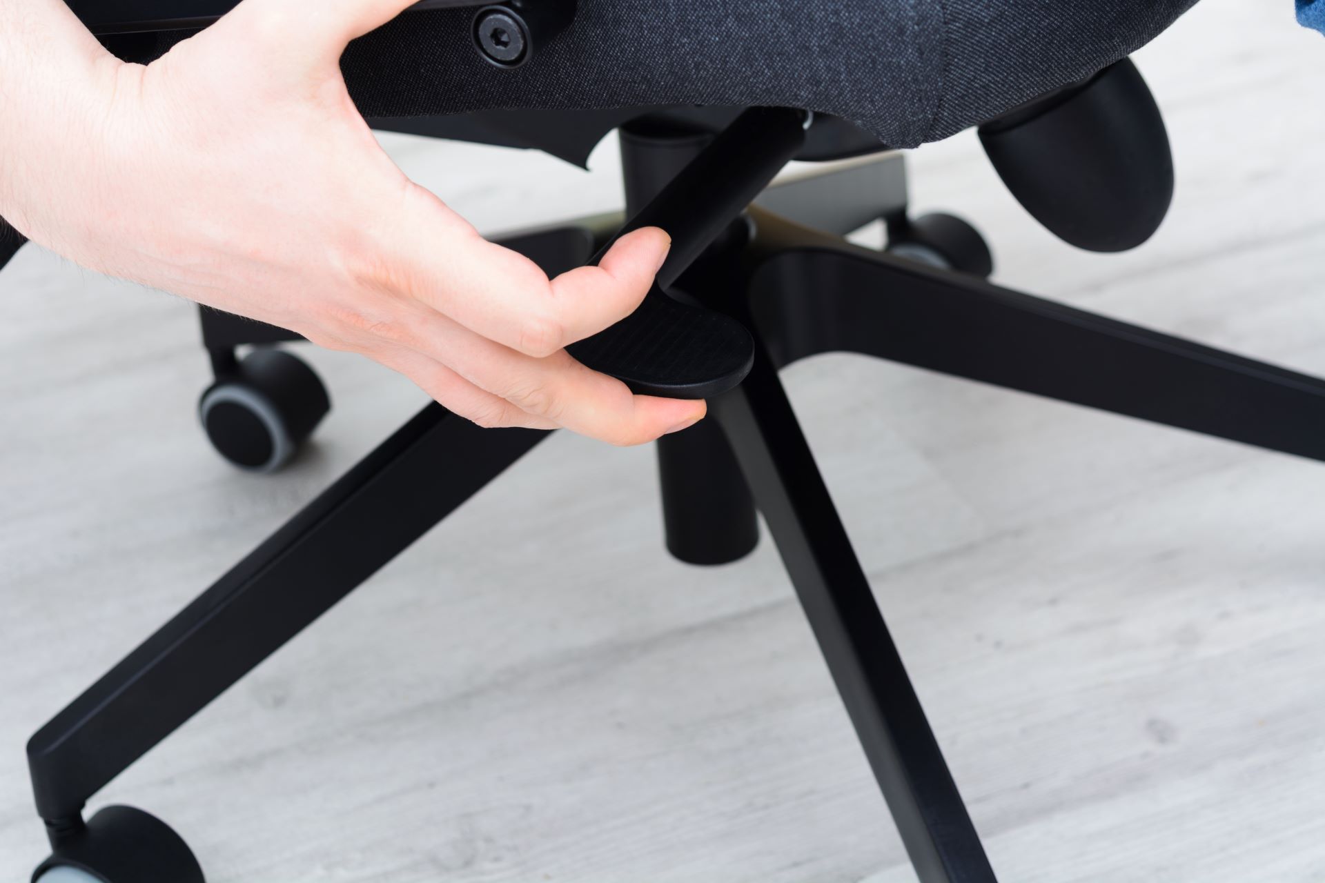 Hand greift nach Hebel unter einem Bürostuhl