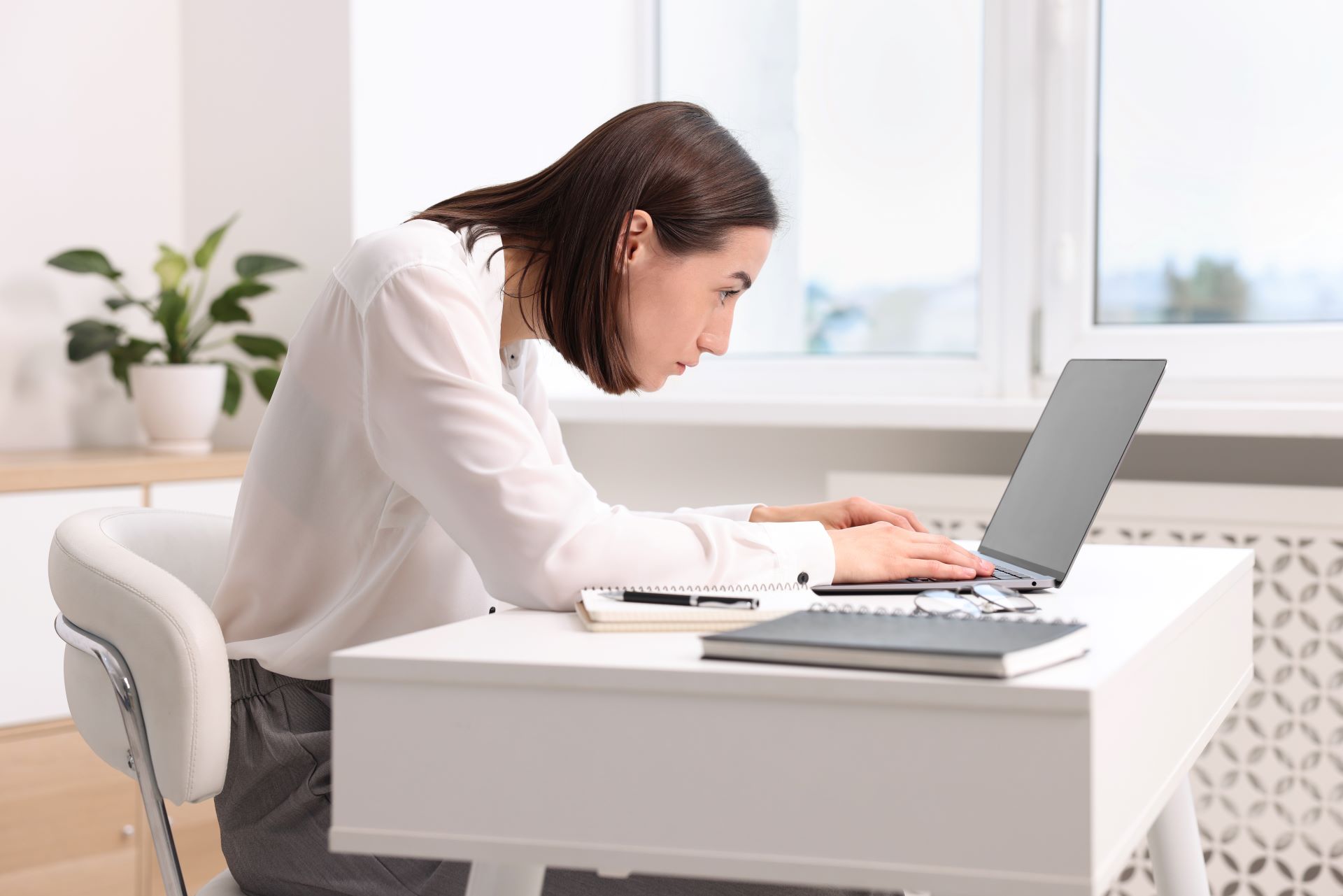 Frau mit schlechter Haltung vor Laptop im Büro