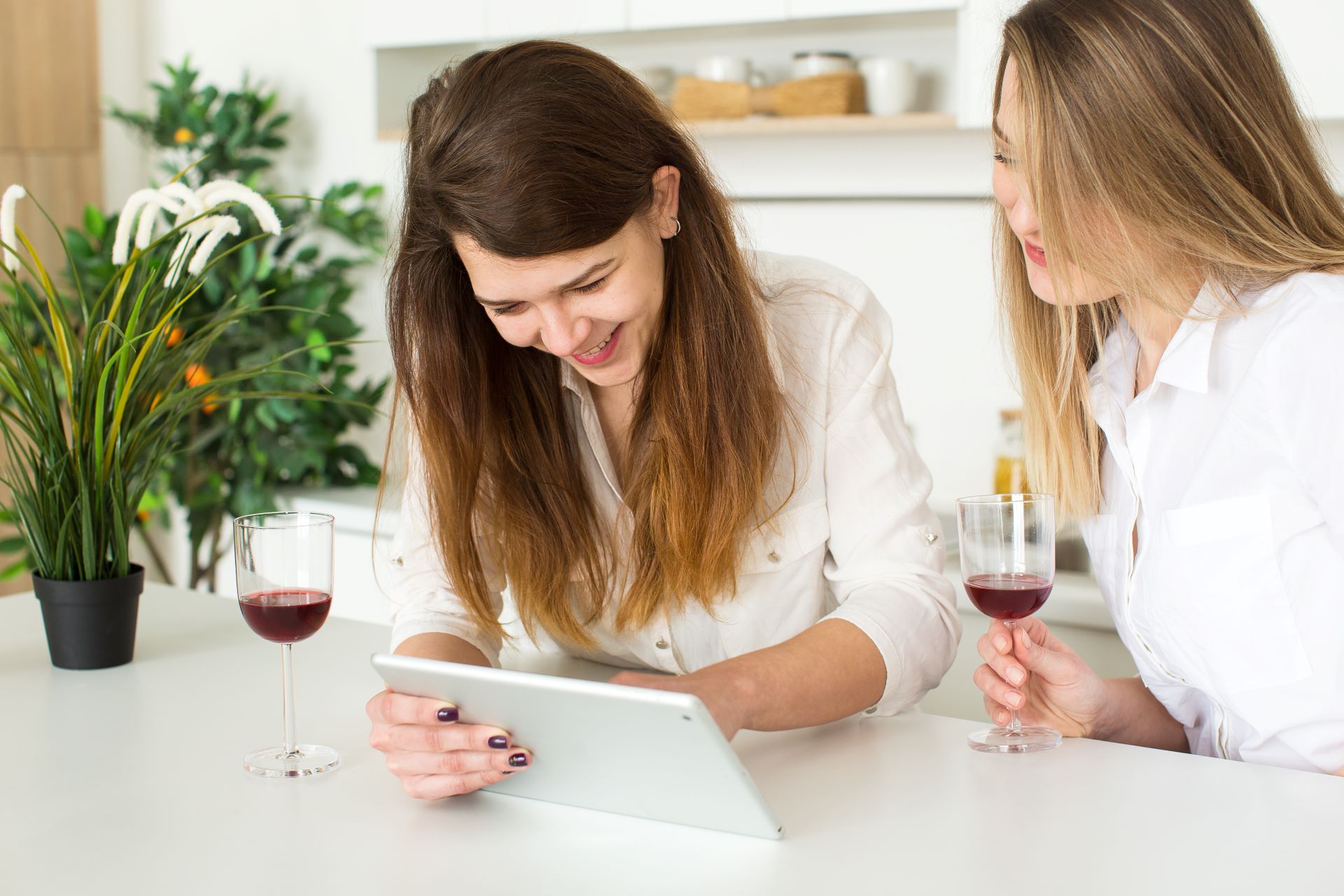 Zwei Frauen vergleichen Weinangebote auf einem Tablet
